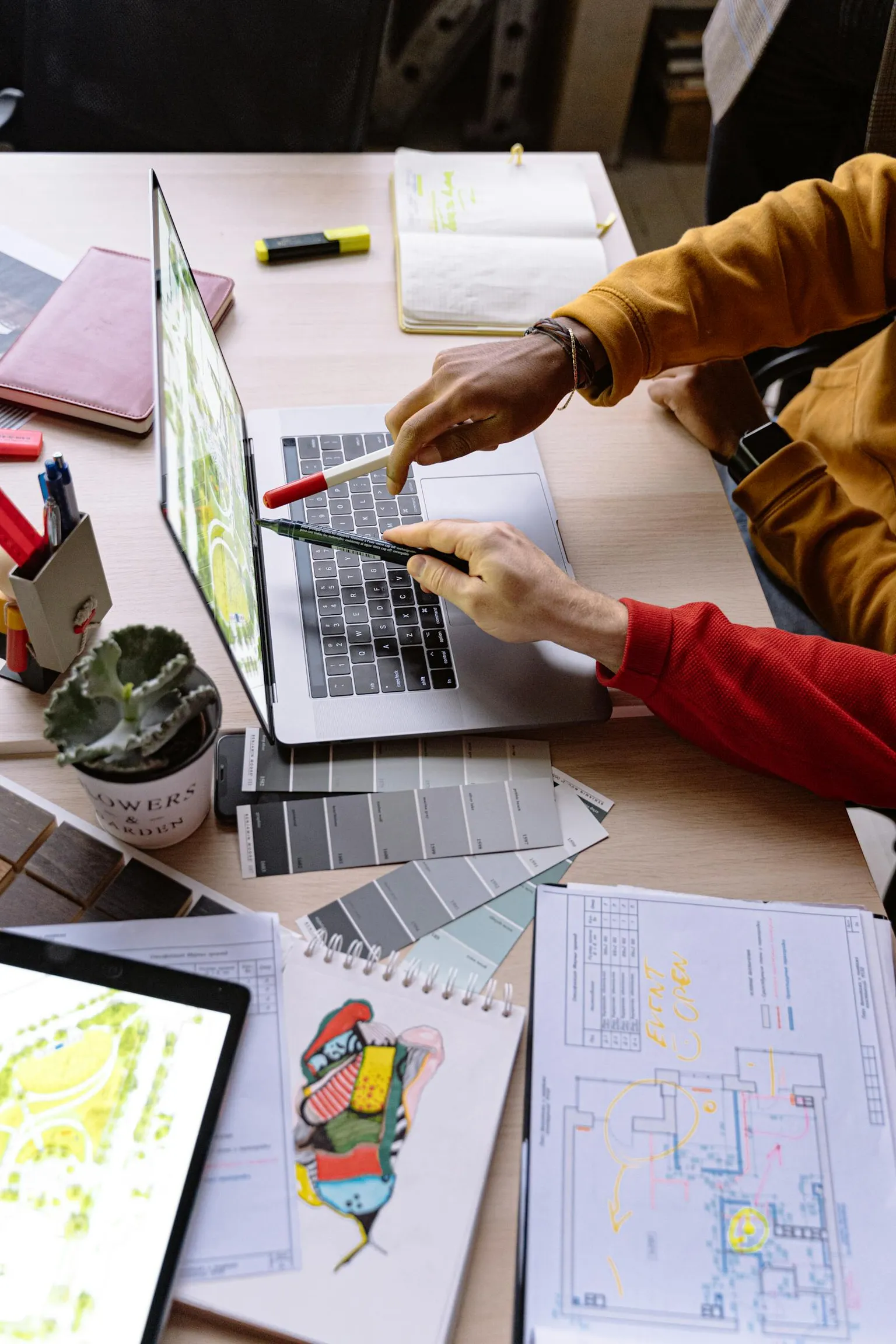 Laptop, Notizen und Entwurfsunterlagen auf einem Arbeitstisch in einem Design- und Konzeptkontext.