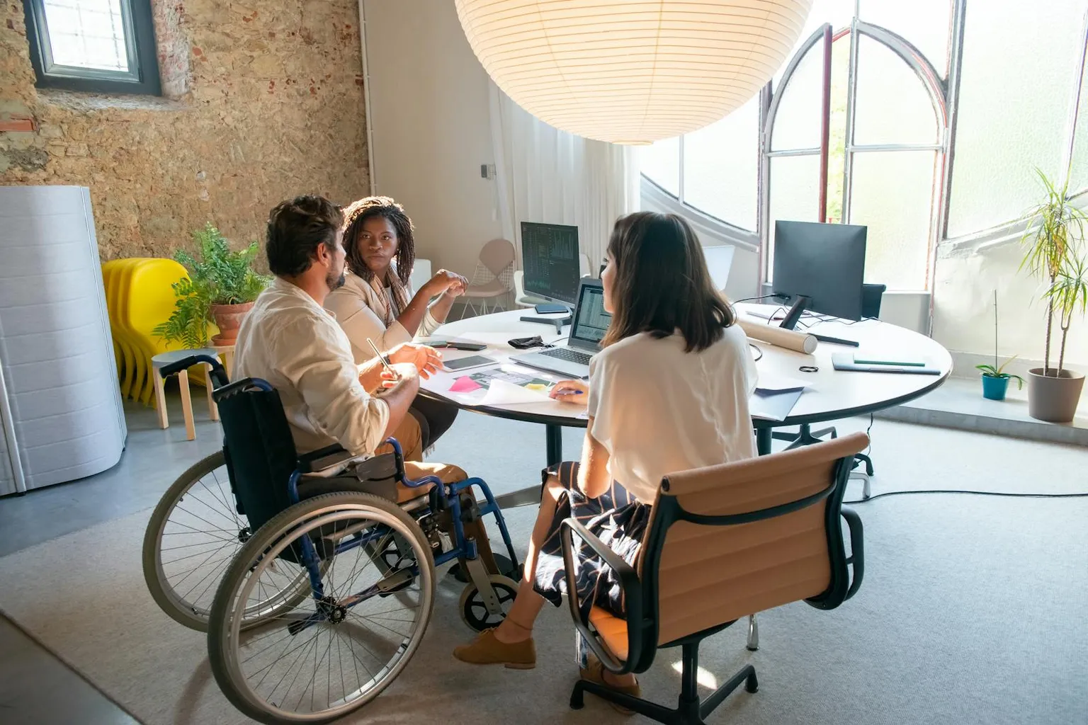 Mehrere Personen in einer freundlichen Office-Besprechung mit offener, professioneller Atmosphäre.