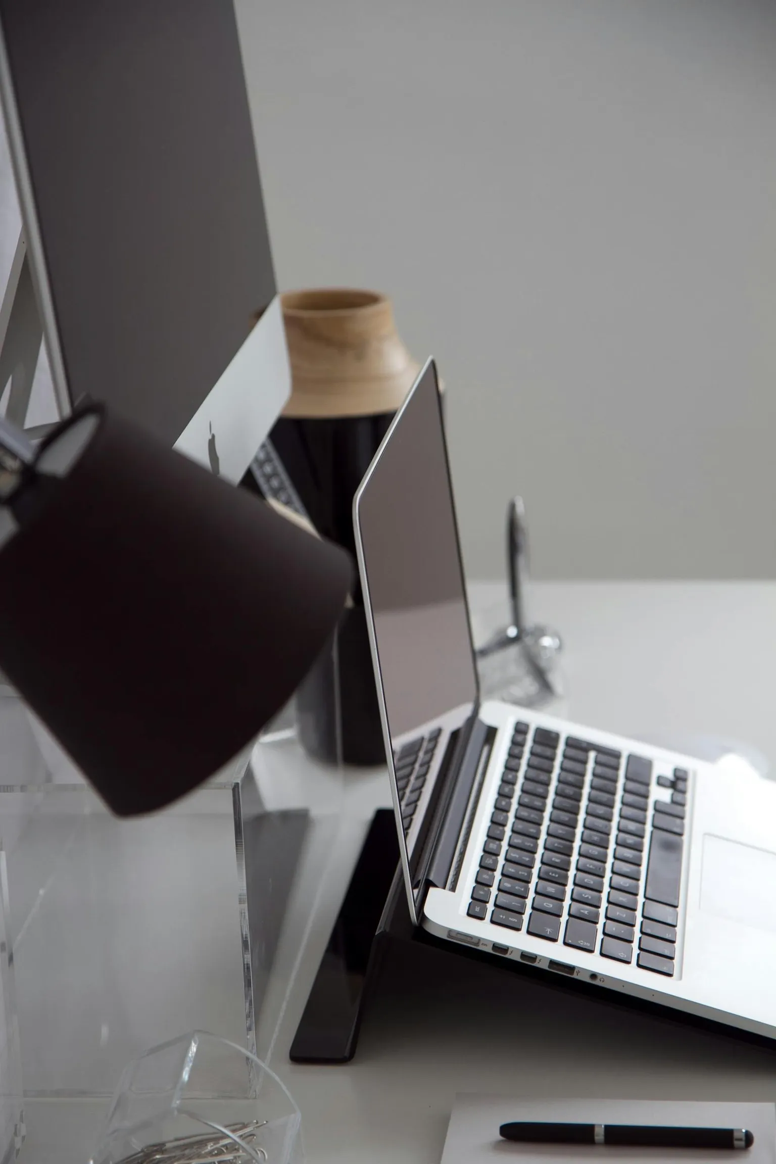 Minimalistischer Arbeitsplatz mit Laptop und Desktop-Monitor in einer klaren Büroumgebung.